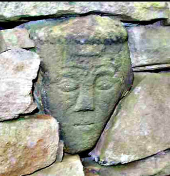 A carved stone head, in a wall near Glossop.